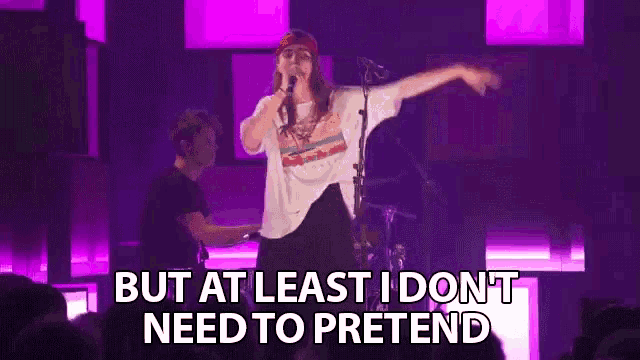 a woman is singing into a microphone on a stage while a man plays a piano .