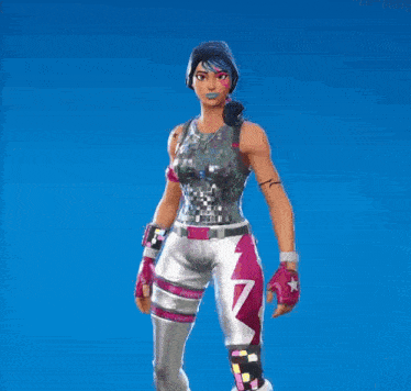 a woman in a silver top and white pants is standing in front of a blue backdrop