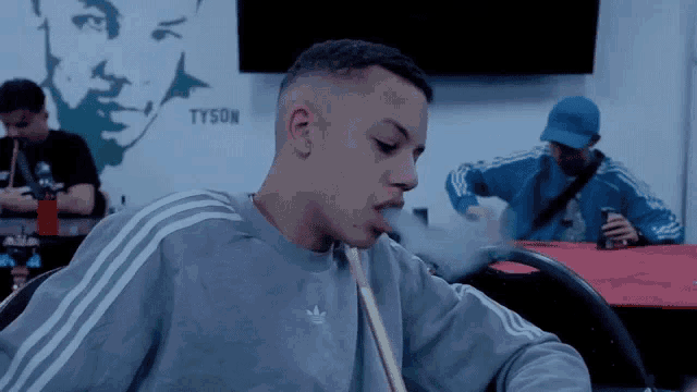 a man is smoking a hookah in front of a wall with tyson on it