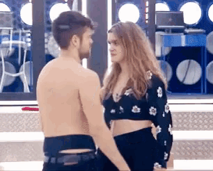 a shirtless man and a woman are looking at each other in a room
