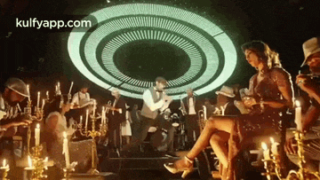 a woman is sitting on a chair in a room with candles and a man is playing a trumpet .