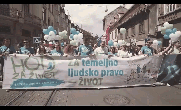 a group of people holding balloons and a banner that says hold za temeljno ljudsko pravo zivot