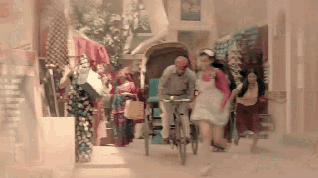 a group of people are walking down a street with a man riding a rickshaw