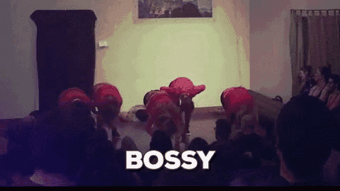a group of people are dancing in front of a crowd and the word bossy is on the bottom of the image .
