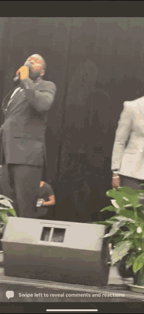 a man in a suit singing into a microphone with swipe left to reveal comments and reactions at the bottom of the screen