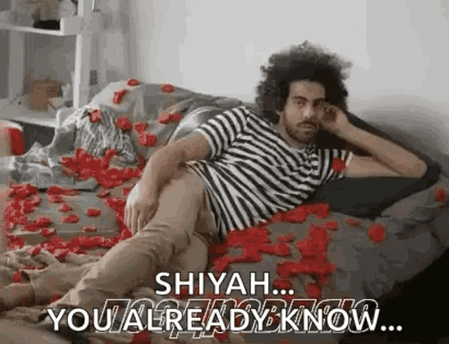 a man is laying on a bed covered in rose petals and talking on his phone .