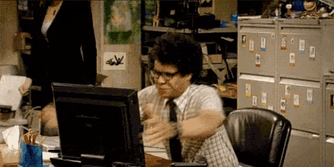 a man is sitting in front of a computer with a sticker on the wall that says ' a ' on it