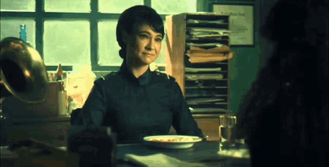 a woman is sitting at a table with a plate of food