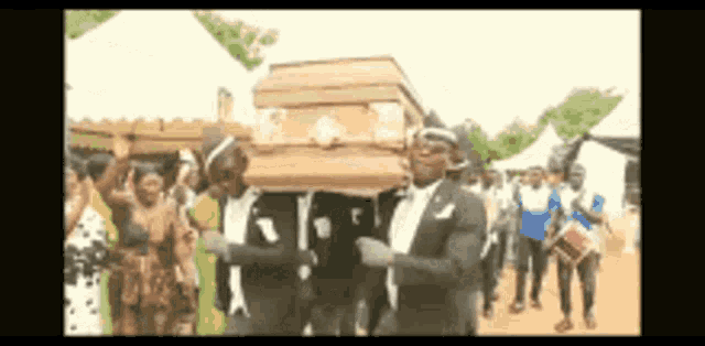 a group of men are carrying a coffin while dancing .