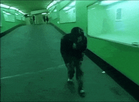 a person is walking down a green hallway in a dark tunnel .