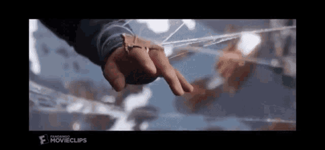 a close up of a person 's hand reaching out towards a spider web .