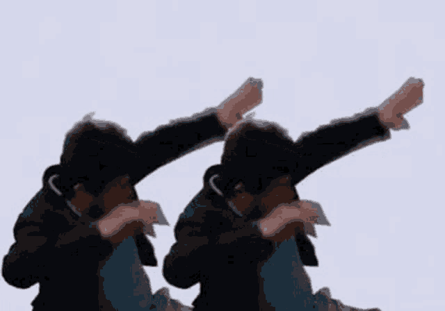 a couple of men are standing next to each other with their arms in the air .