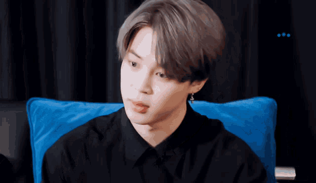 a man in a black shirt is sitting on a blue couch
