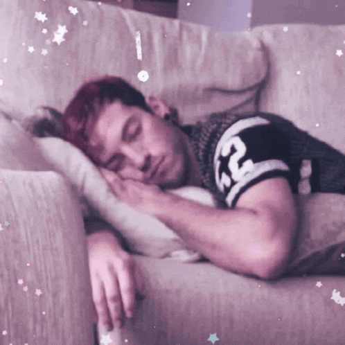 a man with red hair is sleeping on a couch with a shirt that says rc on it