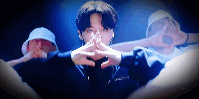 a man is making a heart shape with his hands while wearing a hat .