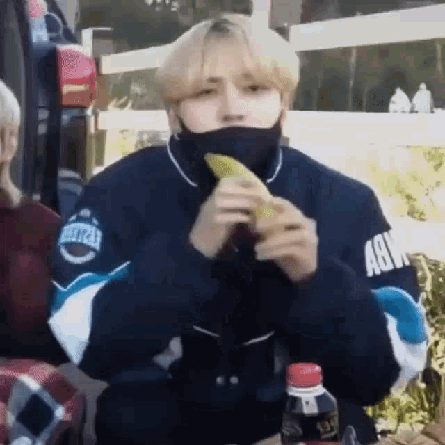 a young man wearing a face mask is eating a banana .