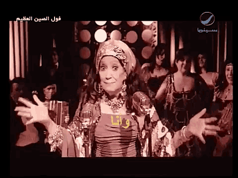 a woman in a red dress stands in front of a microphone with arabic writing on the bottom