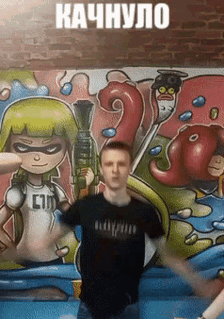 a man is standing in front of a wall with graffiti on it and the word kachnylo is above him