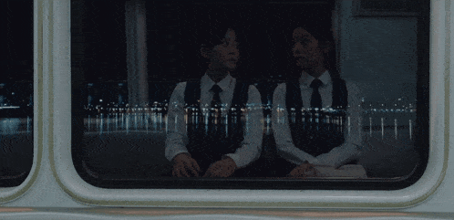 a boy and a girl are looking out a window at night