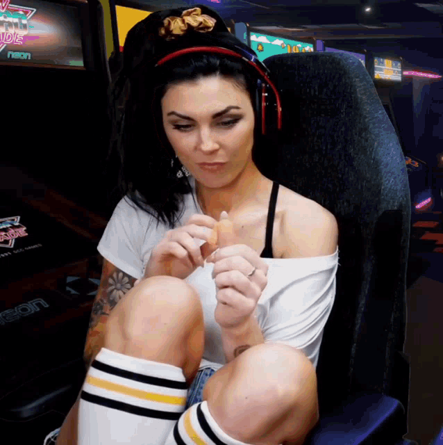 a woman is sitting in an arcade chair with a neon sign in the background