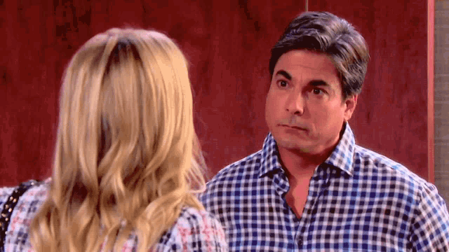 a man in a plaid shirt looks at a woman with blonde hair
