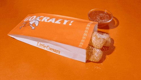 a bag of little caesars food with a bowl of dipping sauce next to it