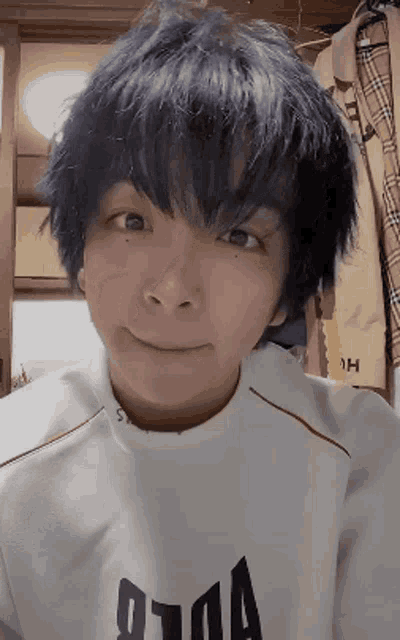 a person with blue hair is wearing a white shirt with the letter a printed on it