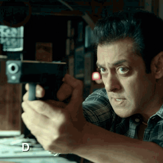 a man holding a gun with the letter d visible