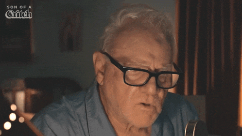 a man wearing glasses and a blue shirt with the words son of a glitch on the bottom right