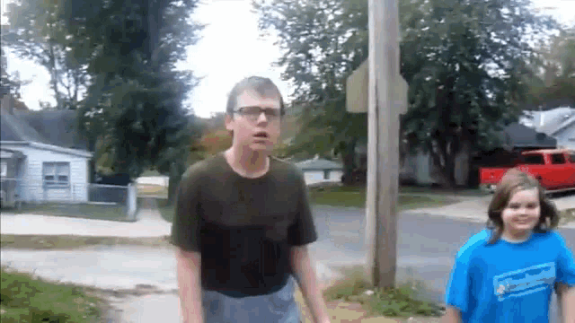 a man and a girl are standing next to each other on the sidewalk .