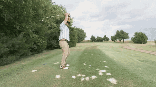a man is swinging a golf club at a golf ball