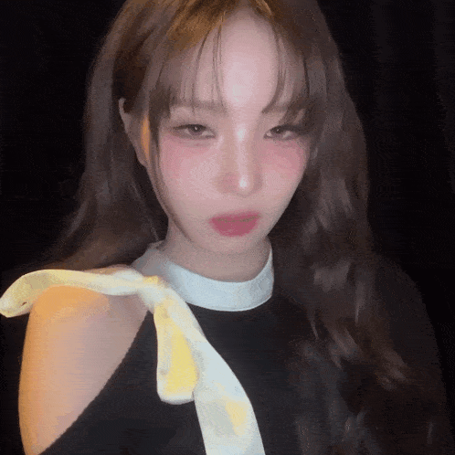 a close up of a woman wearing a black top and a yellow scarf