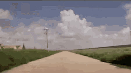 a dirt road going through a green field
