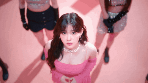 a woman in a pink dress stands in front of a group of other women