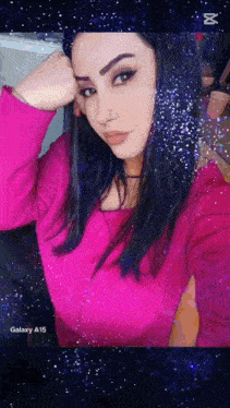 a woman in a pink sweater is taking a selfie with the galaxy a15 in the background