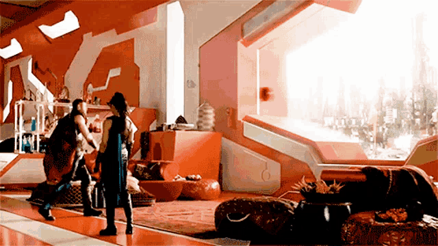 two men are standing in a room with a large window