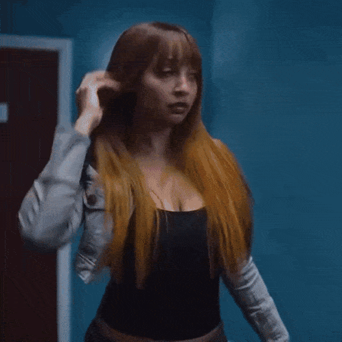 a woman walking down a hallway with blue walls and lights on the ceiling