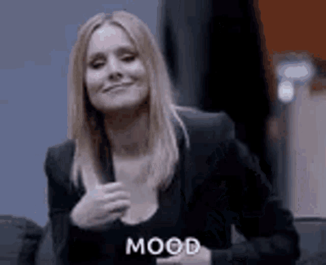 a woman in a black suit is smiling and giving a thumbs up sign .