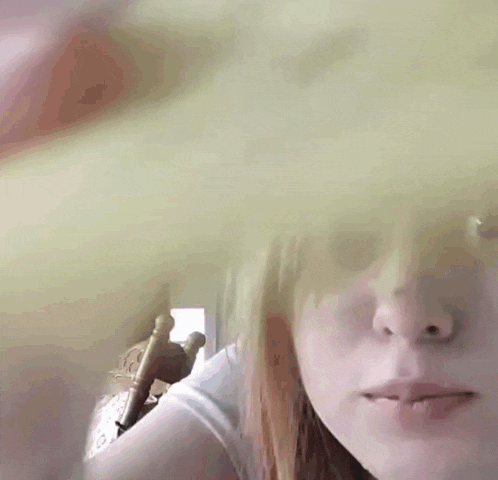 a close up of a girl 's face with a pink object in the background .