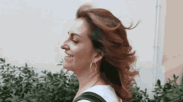 a woman with her hair blowing in the wind is smiling while walking .