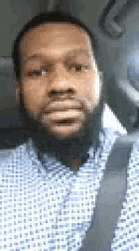 a man with a beard is taking a selfie in a car .
