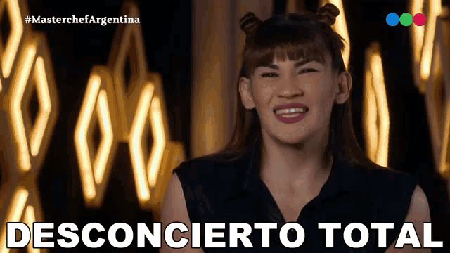 a woman smiles in front of a sign that says " desconcerto total "