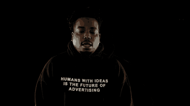 a man wearing a black hoodie that says `` humans with ideas is the future of advertising ''