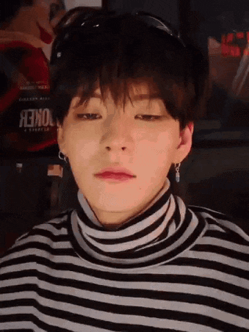 a close up of a young man wearing a striped turtleneck sweater and earrings .