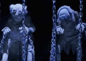 two ghosts are hanging from chains on a swing .