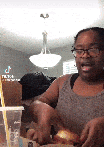 a woman eating a hamburger with a coca cola cup in the background