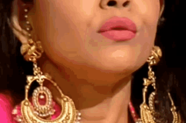 a close up of a woman 's face wearing earrings and lipstick .