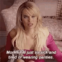 a woman in a pink shirt is sitting on a bed with a pillow .