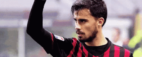 a soccer player with a beard is raising his fist in the air during a game .