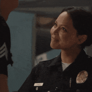 a police officer is smiling while talking to a woman in a room .